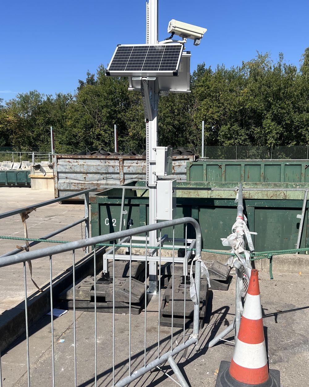 Mât autonome sur base lestée équipé d'une caméra, d'un panneau solaire et de boîtiers techniques, installé sur un recyparc.